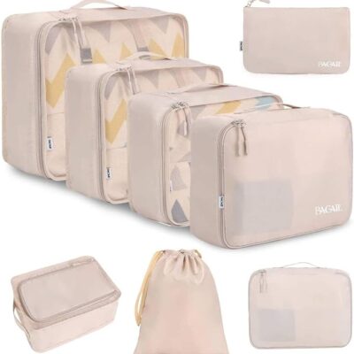 Set of beige packing cubes in various sizes, including zippered pouches, mesh-top cubes, and a drawstring bag, designed for organized travel. The cubes are neatly arranged to show their capacity and versatility for separating clothes and accessories in luggage.